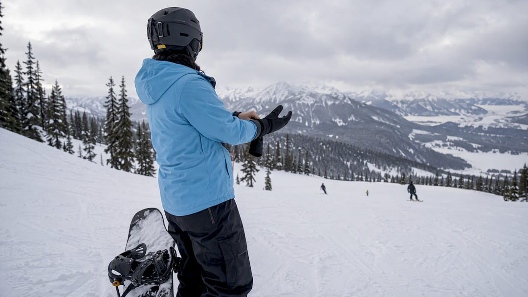 Snowboarder adjusting gloves during a slope break