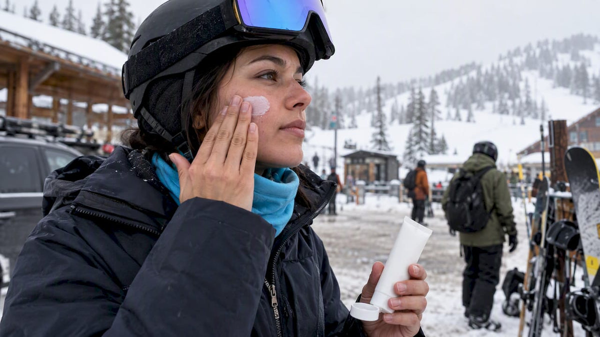 Snowboarder applying sunscreen before raising face covering